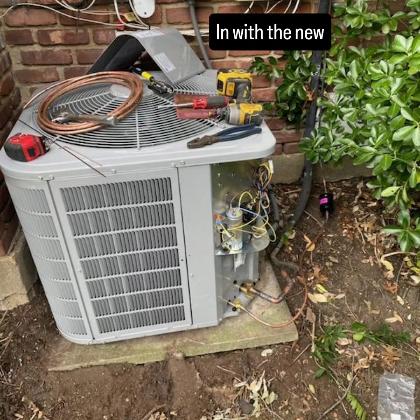 New outdoor AC condenser being charged with refrigerant, tools on top